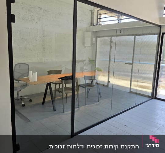 מחיצת זכוכית ודלת זכוכית עם פרופיל שחור בחדר משרדי